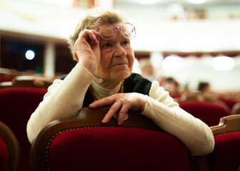 Elderly woman enjoying performance at opera and ballet theater