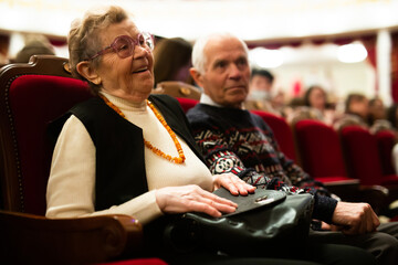 Mature spouses are interested in watching ballet performance in the theater hall
