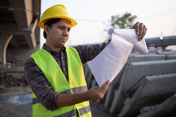 Asian construction workers looking at construction plans at the job site.