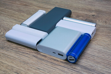 Set of power banks of different sizes on a wooden table. Choosing a portable charger.
