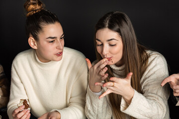 girls lick their fingers while eating chocolate cream desserts
