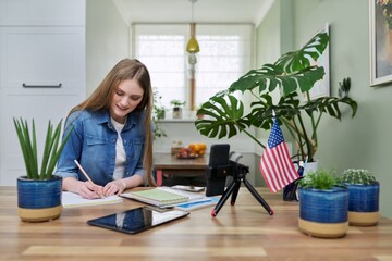 Young woman student studying at home online remotely, USA flag background