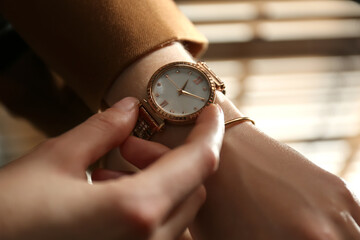 Woman wearing luxury wristwatch indoors, closeup of hand