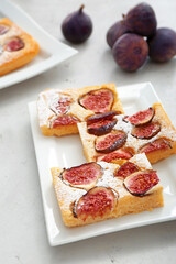 Plate with slices of delicious fig pie on light background