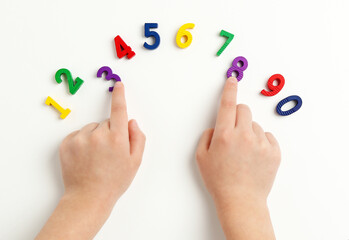 Children's hands move numbers on a white table. Early education. Learning colors and to count from zero to ten