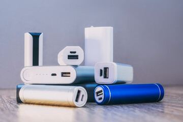 Set of power banks of different sizes on a wooden table. Choosing a portable charger.