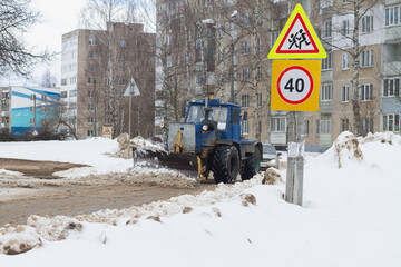 Tractor clears snow with a bucket in winter on the road with a bucket
