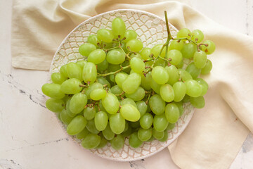 Plate with ripe green grapes on white background