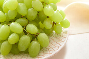 Plate with ripe green grapes on table, closeup