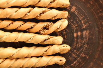Grissini bread sticks with sesame seeds in a clay plate, close-up
