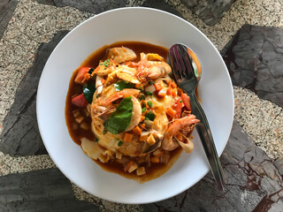 Food and cutlery in white plates Placed on marble table in a rural restaurant in Thailand. Dinner consisted of egg, shrimp, coriander, kaffir lime leaves, and sauce. Selective focus. Closeup top view.