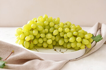 Plate with ripe green grapes on white background