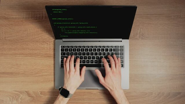 Closeup a man's hands are typing commands of a laptop keyboard. A man is writing a program. The developer is coding. Code on the laptop screen. Concept of programming and development web.