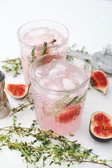 Glass of tasty fig lemonade on light background