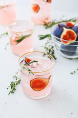 Glasses of tasty fig lemonade on light background