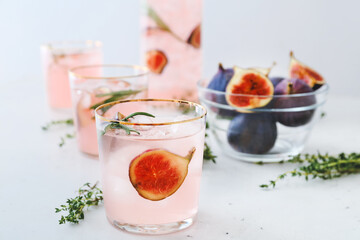 Glasses of tasty fig lemonade on light background