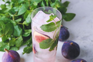 Glass of tasty fig lemonade on light background