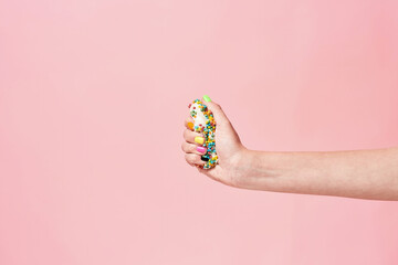 Say no to sugar. Female hand squeezing donut on pink background