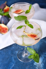 Glasses of tasty fig lemonade on color background