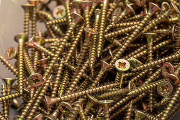 A handful of self-tapping screws made of steel. Construction abstraction. Industrial background.