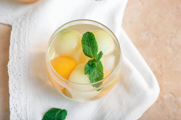 Glass of cold melon cocktail on color background
