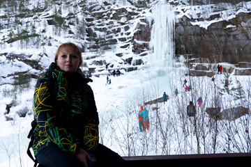 A girl in a sports winter suit sitting on the railing.