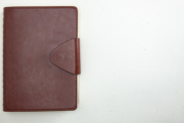 closed notebook in a leather cover with a clasp on a light background without people a place for text