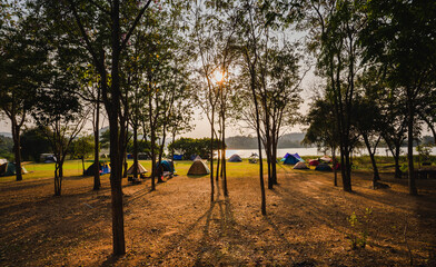 Tourist tent camping under the tree forest near the lake and beautiful sunlight.