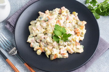 Olivier salad with mayonnaise on a plate. Russian is a traditional festive dish.