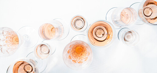 Sparkling rose wine in different glasses on white background.