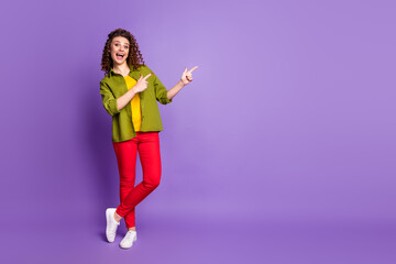 Full body photo of crazy amazed girl promoter point index finger copyspace present incredible adverts promo wear style stylish outfit shoes isolated over purple color background