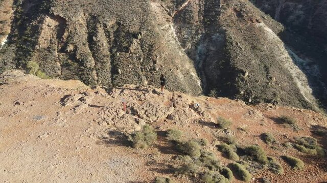 Young Female Traveller Stand Front To Spectacular Cliff Precipice At Sunrise Falling Over Charles Knife Canyon Exmouth, Western Australia, Aerial Orbit Drone Shot