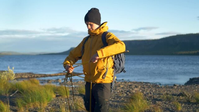 Young Camper unfolding camping tent poles amidst Swedish wilderness - Medium slow motion shot