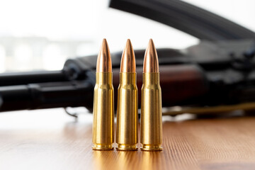 Three bullets against blurred Kalashnikov assault rifle background. Cartridges 7.62 caliber for ak...
