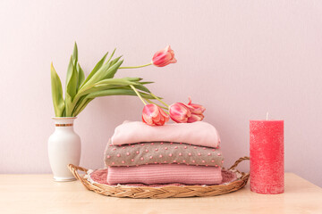 Stack of folded wool knitted sweaters or pullovers in pink pastel colors and mag on table with...