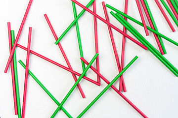 red and green cocktail straws lying mixed up on white background