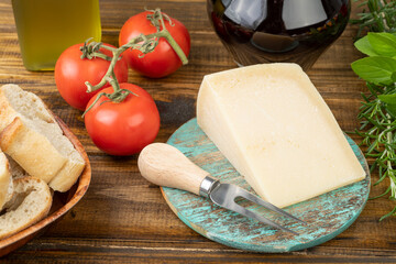 Parmesan cheese, tomatoes, olive oil, wine, bread and herbs over wooden table. Mediterranean food
