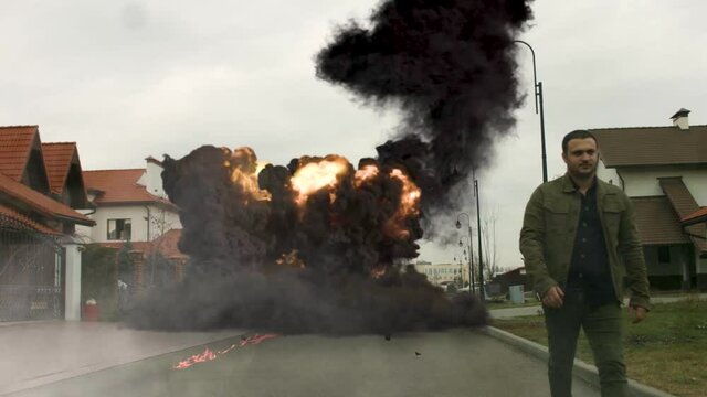 cool guy walks in the background of a car explosion
