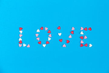 small white, pink and red hearts forming a word Love on blue background