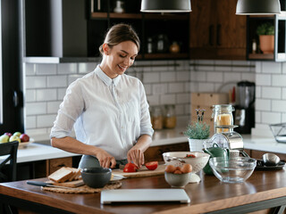 Fototapeta na wymiar Happy woman enjoying in the kitchen. Beautiful woman making salad