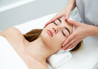 Fototapeta na wymiar Beautician massaging woman's face. Attractive girl having facial treatment and massage.