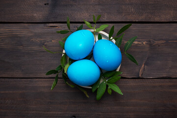Easter eggs painted by hand colored on a dark wooden table, top view, copy space.