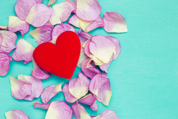Fototapeta premium Closeup red heart on pink rose leaves on blue background, vintage tone style, love and romance concept, valentine card background idea