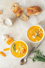 Bowls of tasty carrot cream soup on light background