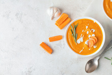 Bowl of tasty carrot cream soup on light background