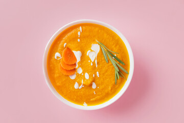Bowl of tasty carrot cream soup on color background