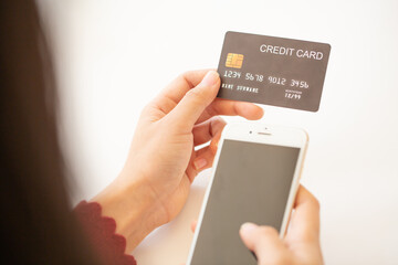 Close up woman hand using credit card and smartphone laptop for buying online shopping