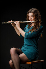 Portrait of a woman playing a transverse flute, isolated on a black background.