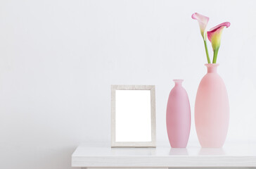 beautiful pink flowers in vases  and wooden frame on white background