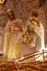 Three wise men or kings in adoration of the newborn baby Jesus, porcelain figurines on straw, Christmas nativity scene